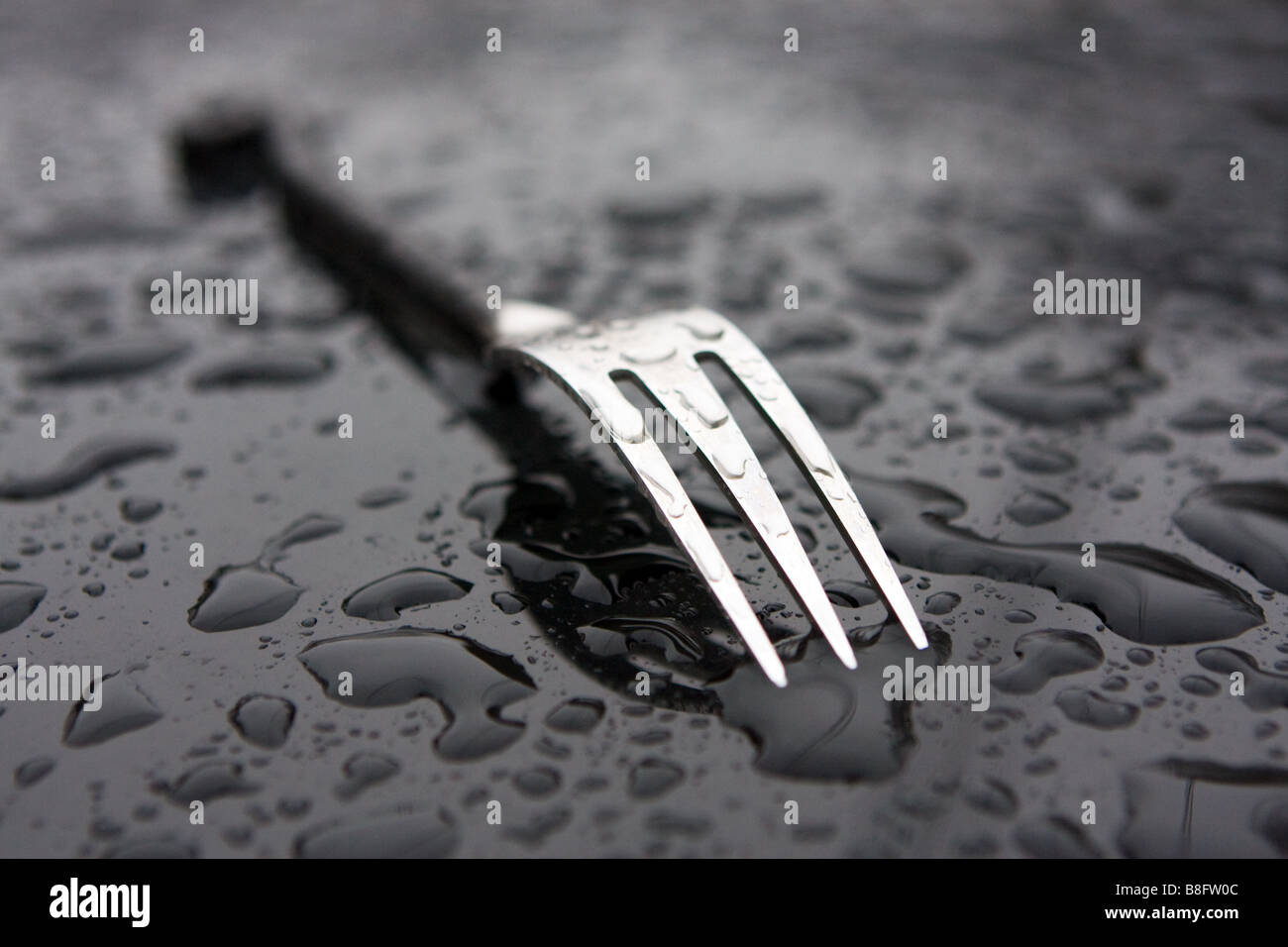 Una forcella di cena su una superficie metallica liscia con gocce di pioggia Foto Stock