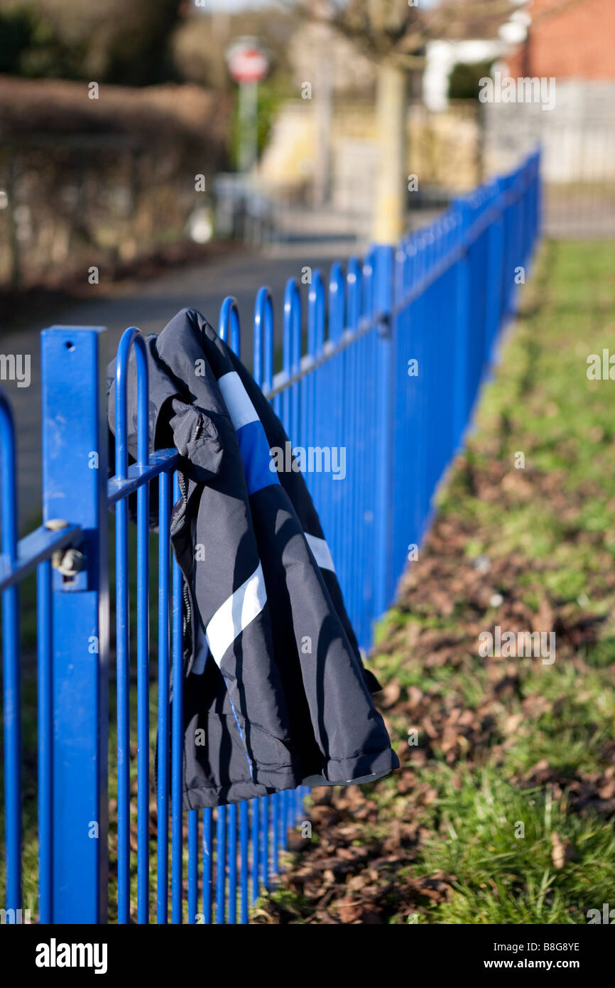Un cappotto perso si blocca su un recinto di blu Foto Stock
