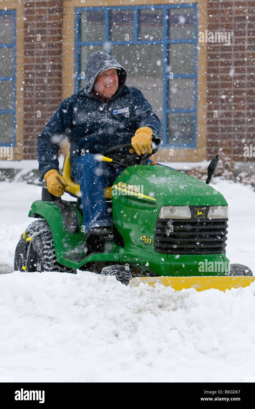 John Deere riding tosaerba dotato di Snow Plough rimozione neve da un parcheggio a Boise Idaho USA Foto Stock