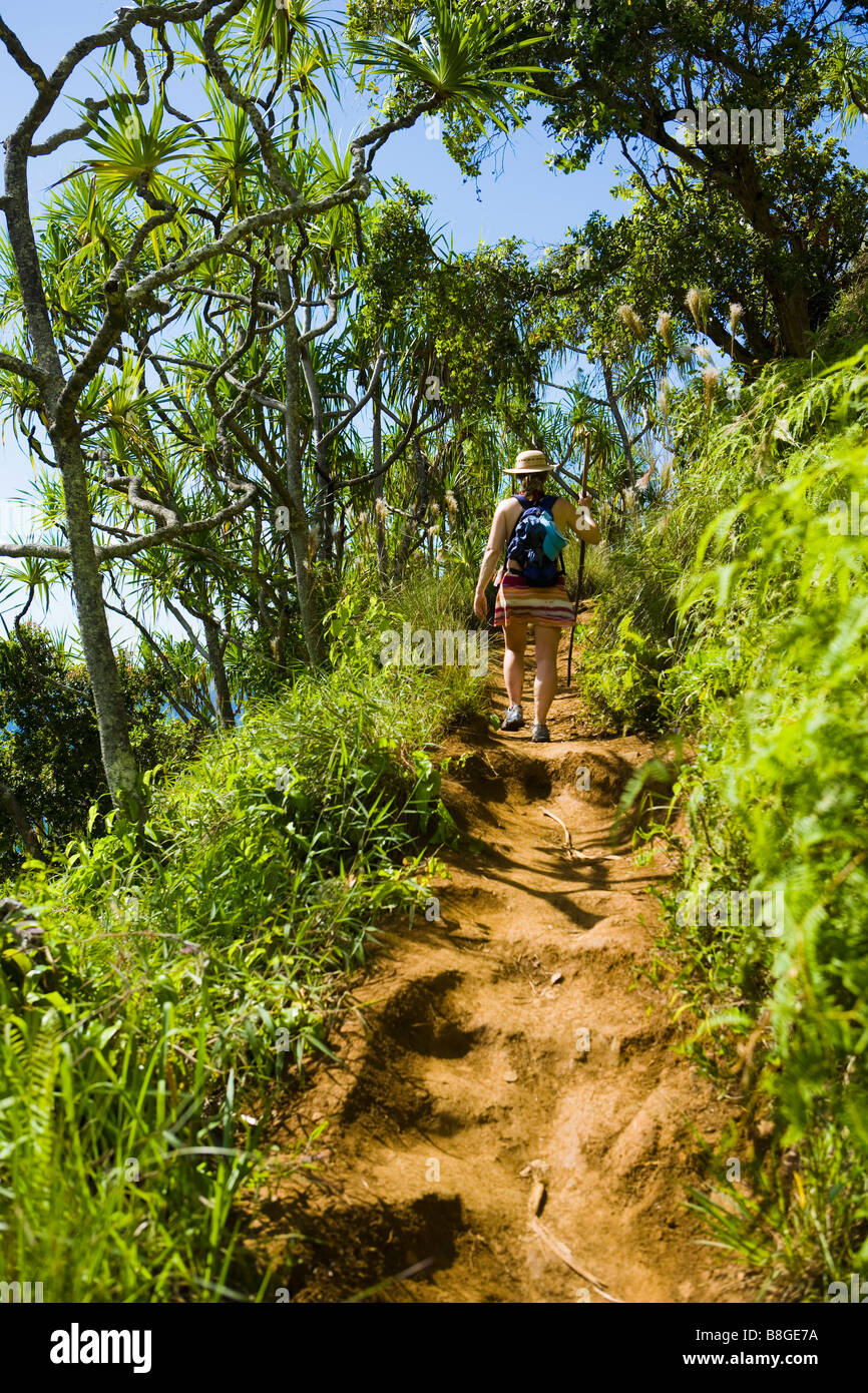 Donna che cammina con un personale a piedi attraverso una foresta tropicale sulla Costa di Na Pali di Kauai Hawaii Foto Stock