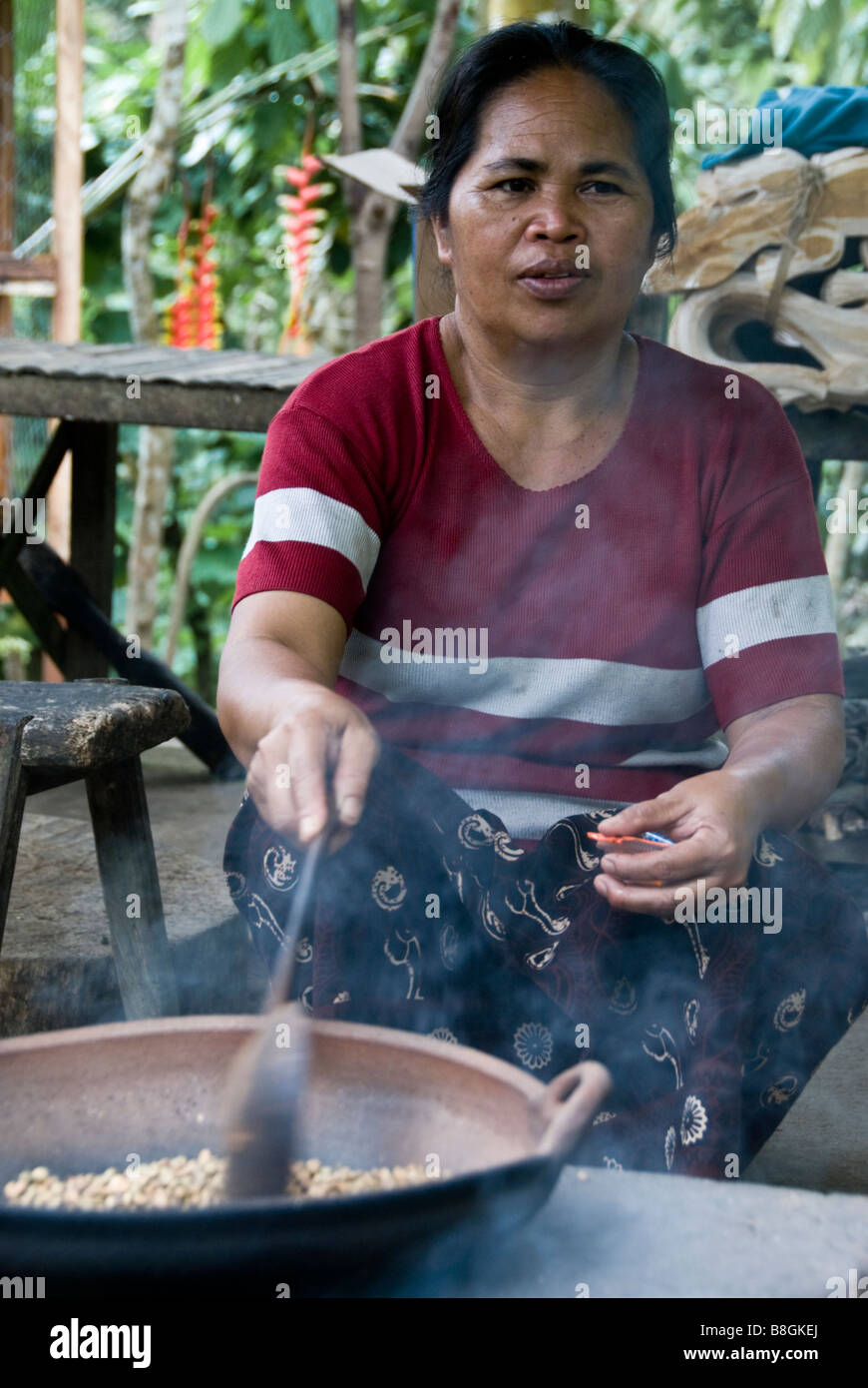 Donna indonesiano la tostatura i chicchi di caffè in Bali Foto Stock