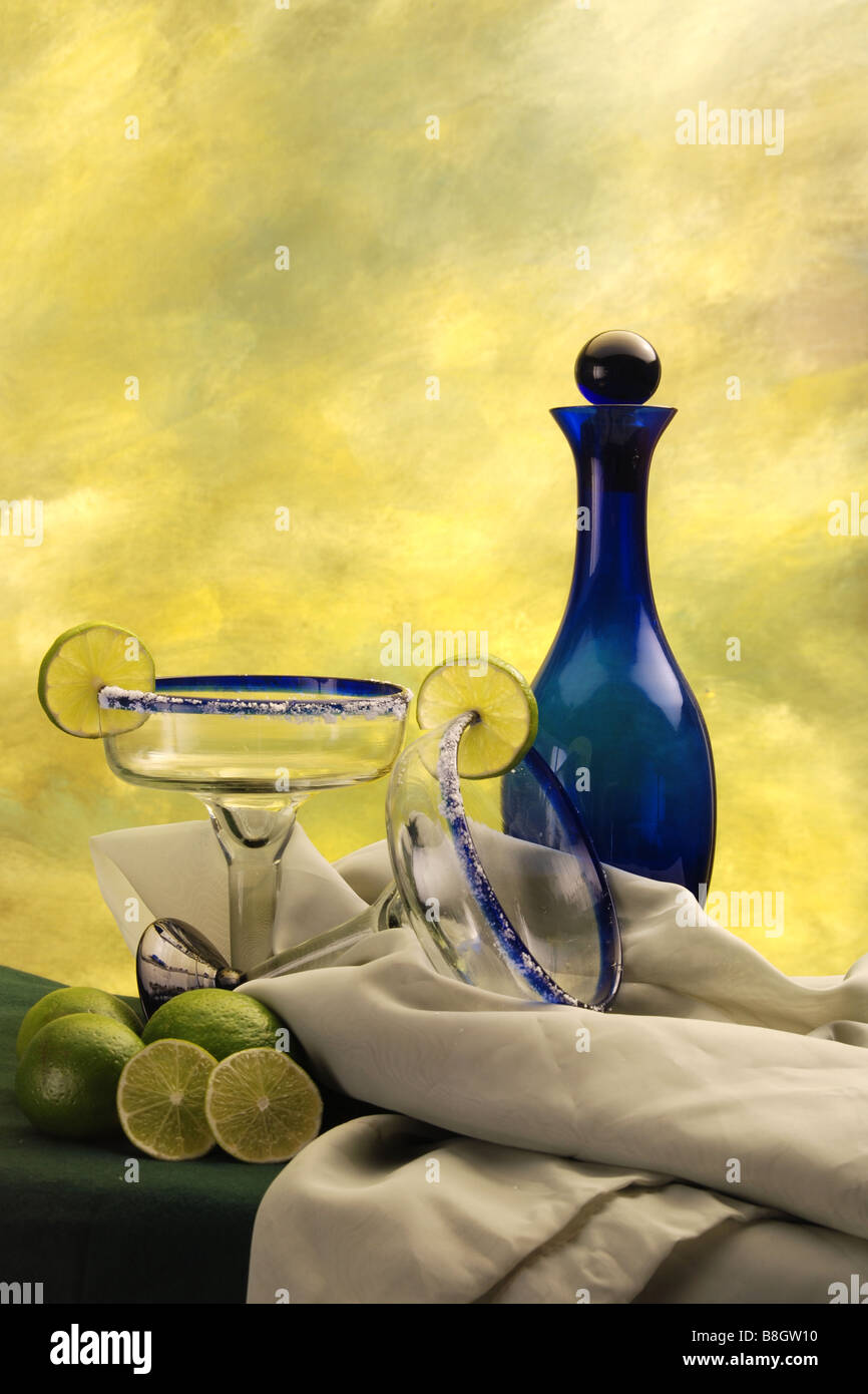 2 bicchieri di Margarita con sale, calce e colbalt bottiglia blu Foto Stock