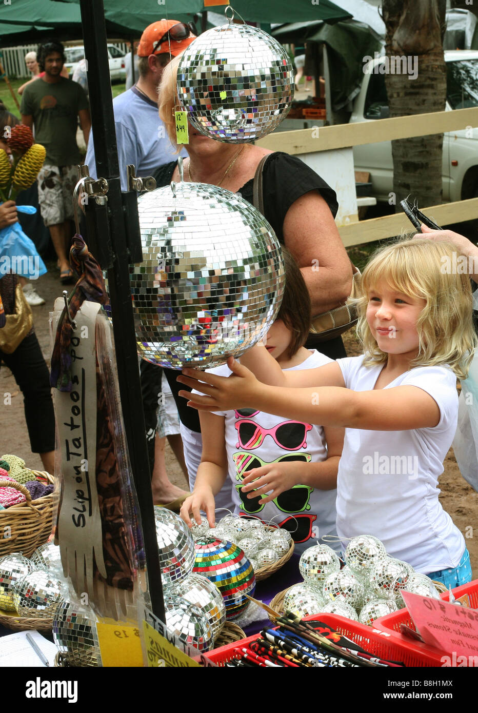 Una giovane ragazza controlla se stessa in una sfera a specchio per la vendita in un mercato all'aperto a Bangalow NSW Australia Foto Stock