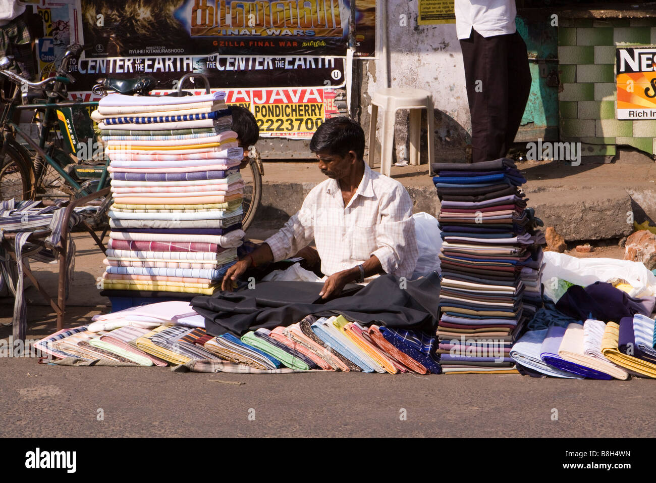 India Pondicherry MG Road uomo disponendo tessili per la vendita in strada mercato domenicale Foto Stock