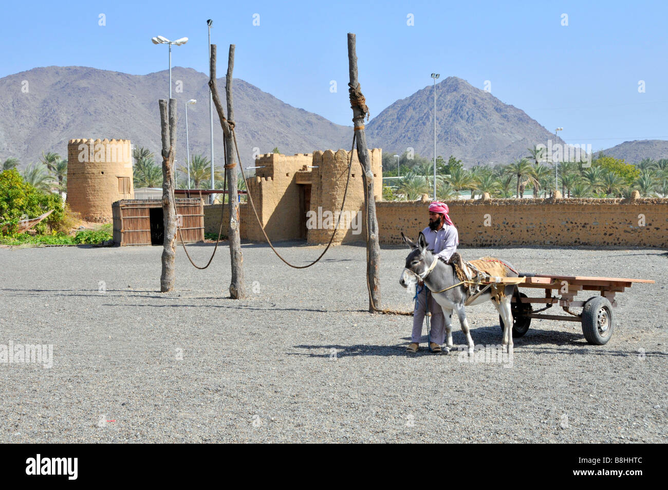 Fujairah Heritage Village recinto murato con uomo arabo accanto asino e carrello Foto Stock