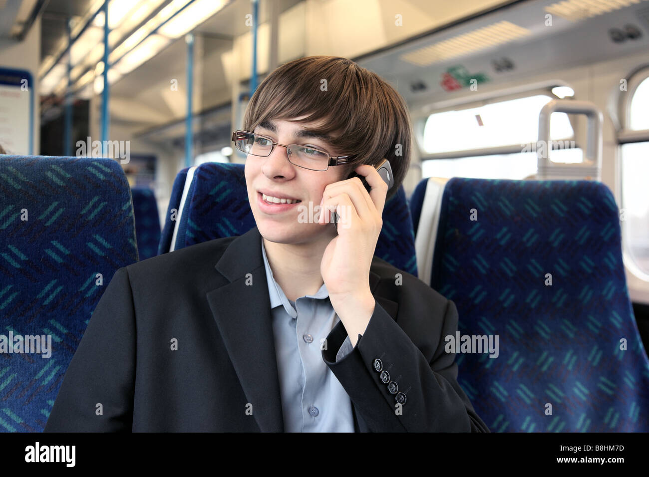 Un giovane maschio utilizzando un cellulare o un telefono cellulare su un treno Foto Stock