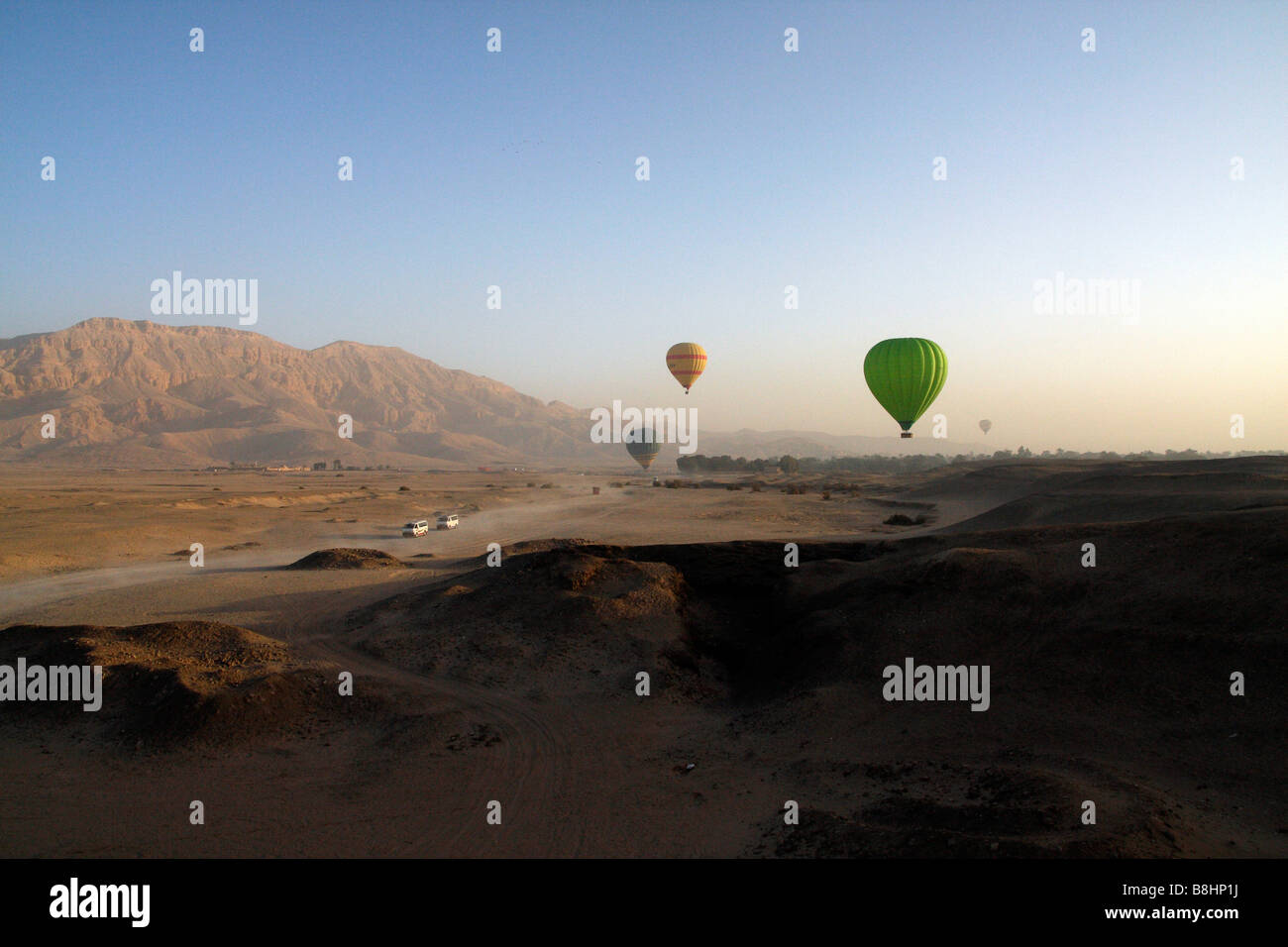 I palloni ad aria calda volare sopra il deserto i villaggi e i campi nei pressi di Habu tempio vicino a Luxor sul Nilo in Egitto Foto Stock