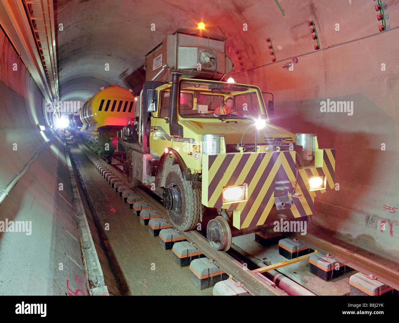 Unimog strada-ferrovia a trazione della macchina funziona un treno di pulizia sulla nuova posa railtracks in una sezione del Channel Tunnel Rail tunnel. Foto Stock