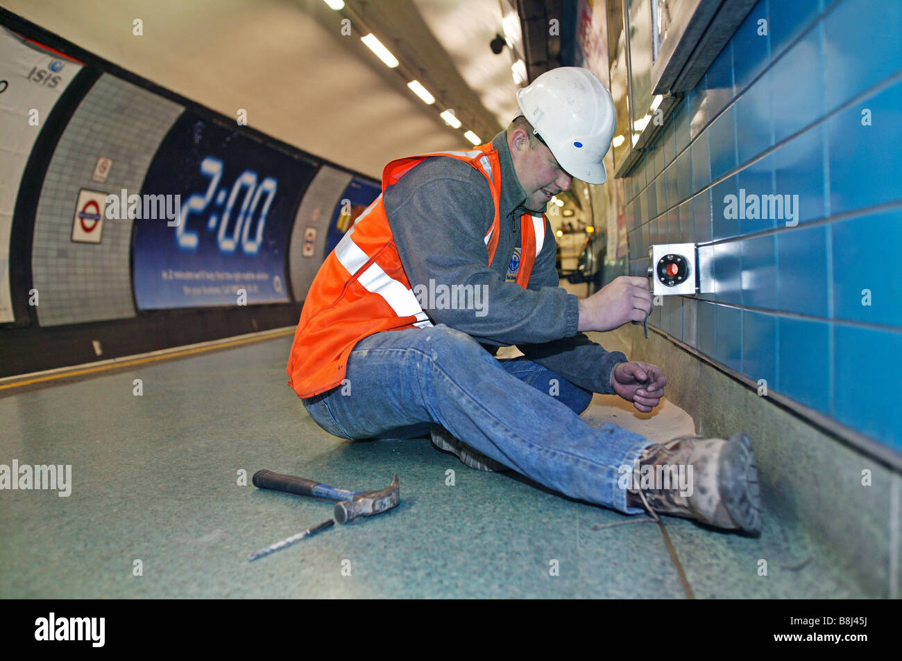 Contraente installazione prisma bersaglio nella stazione della metropolitana per rilevare movimento strutturale causato da vicino i lavori di costruzione. Foto Stock