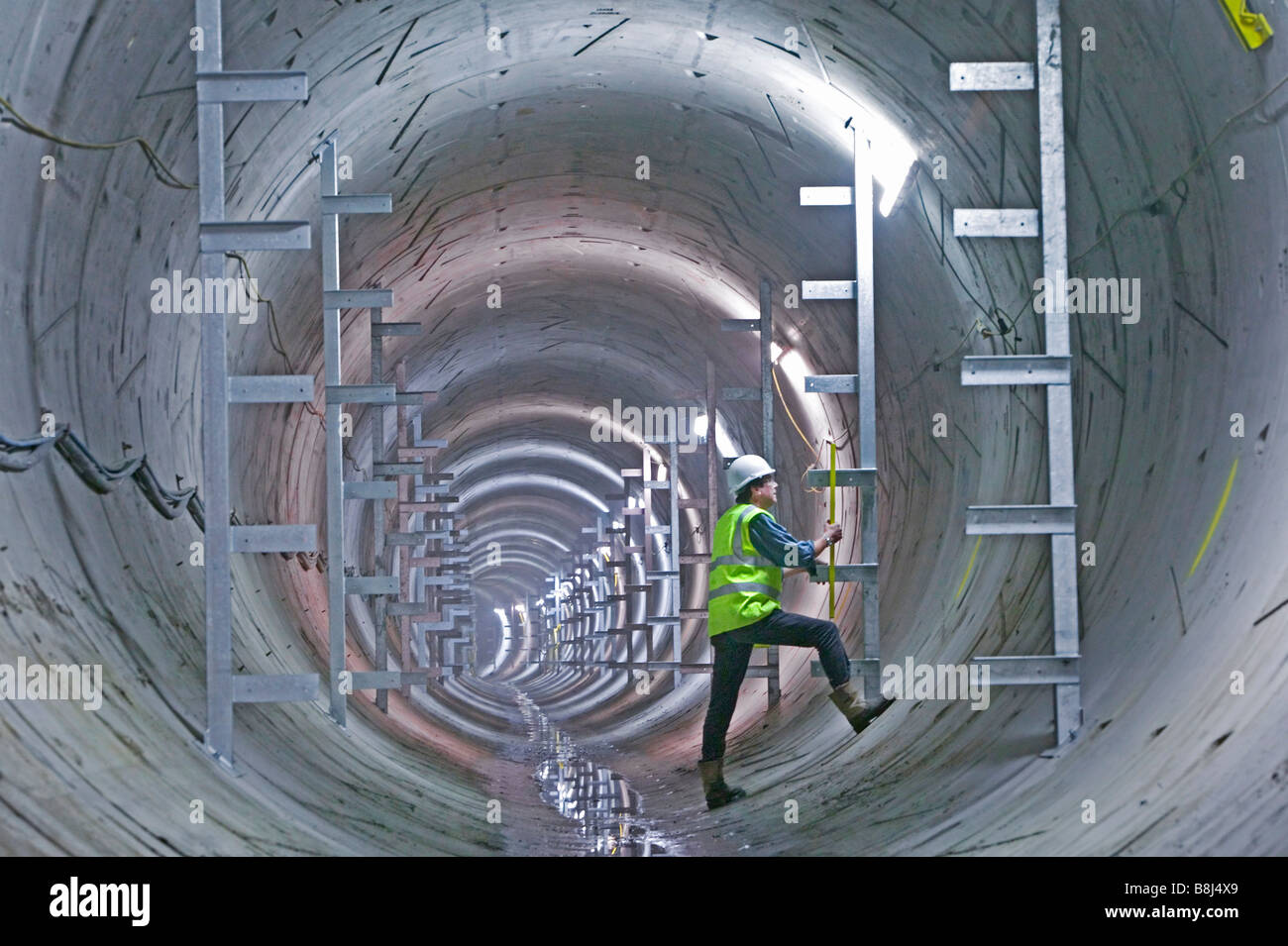 Ingegnere esamina appena installato staffe che effettuerà le attrezzature permanenti per essere installato in questo cavo di alimentazione tunnel. Foto Stock