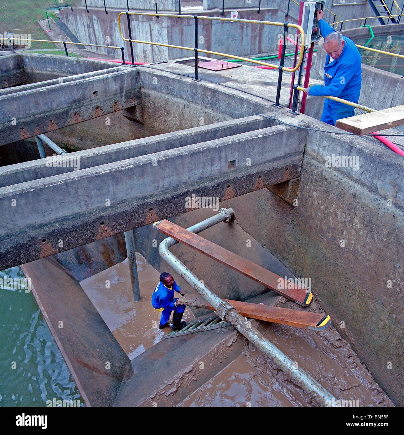 Pulizia dei lavoratori fanghi provenienti da un serbatoio di insediamento presso un impianto di trattamento delle acque in Sud Africa. Foto Stock