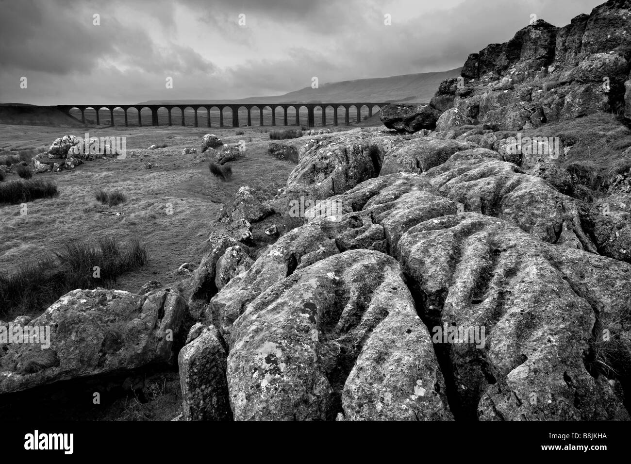 Nuvole temporalesche sulla pavimentazione di pietra calcarea con Ribblehead il viadotto in distanza, Ribblesdale, Yorkshire Dales, North Yorkshire Foto Stock
