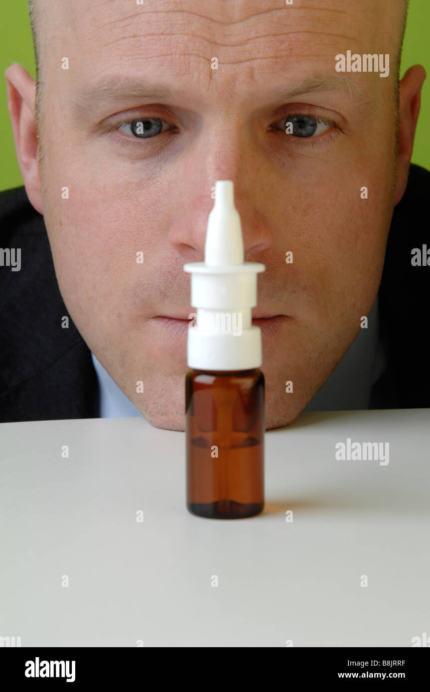 Uomo in un vestito con un influenza utilizzando nosal spray. Foto Stock