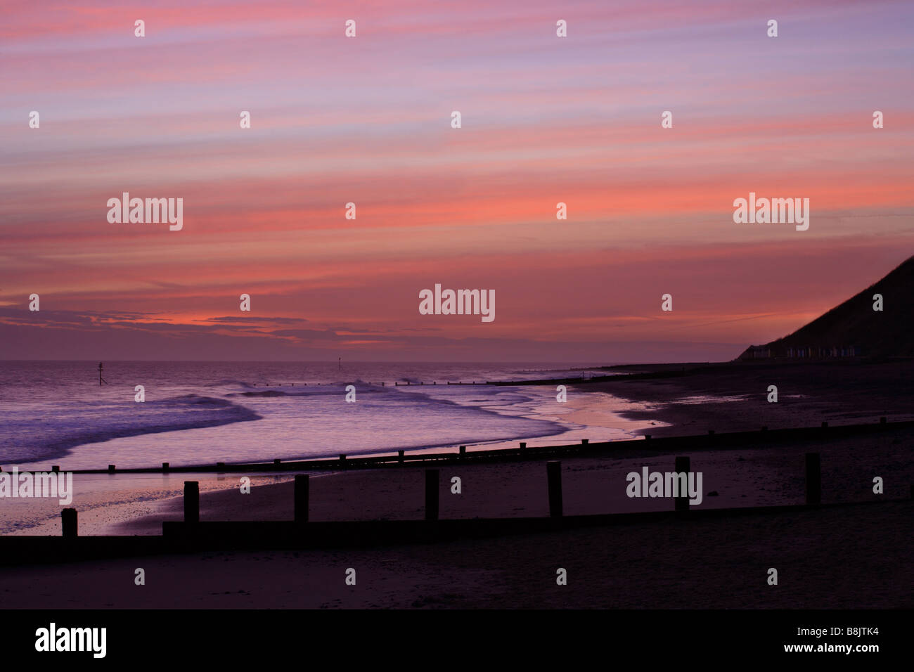 "Norfolk Sunrise' Cromer Beach guardando ad Est verso Overstrand. Pennelli in legno attraversare la spiaggia. Foto Stock