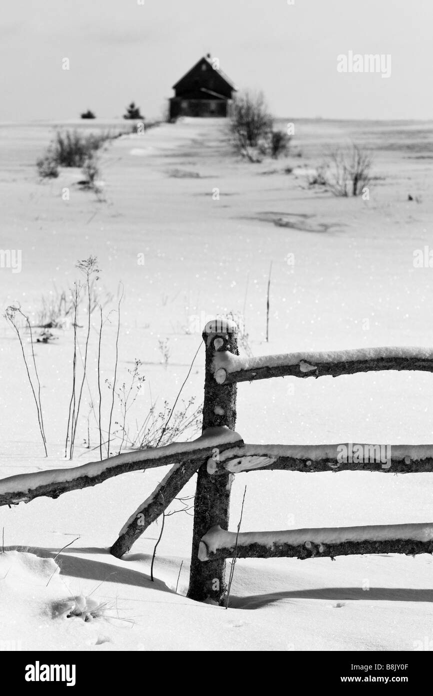 La vecchia casa colonica e una recinzione in un campo nevoso in inverno. Foto Stock