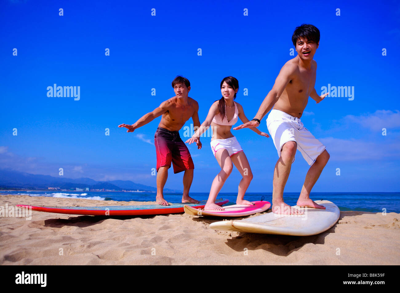 Tre persone in piedi sulla tavola da surf e rendendo la posa di surf Foto Stock