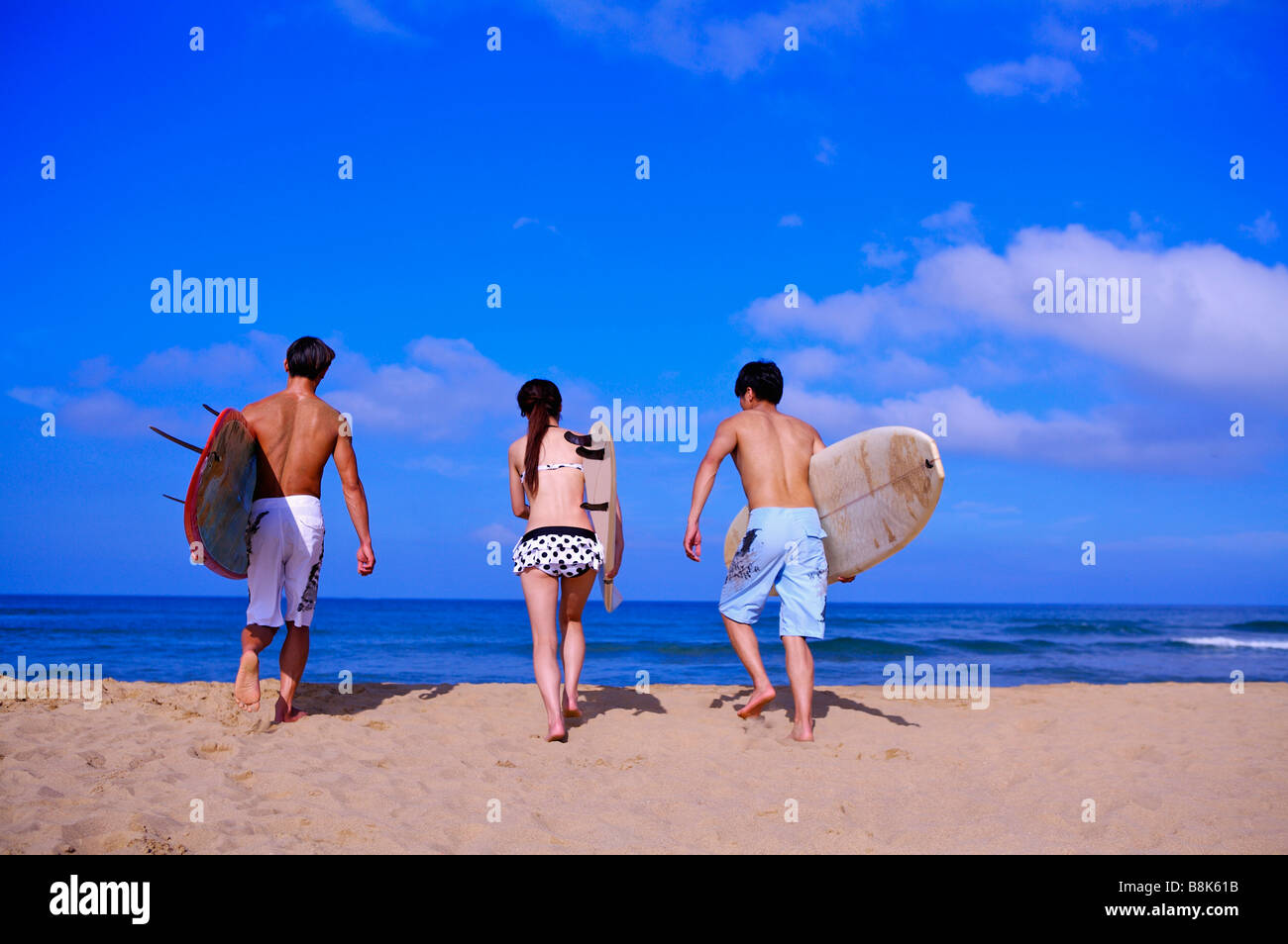 Tre persone che trattengono le tavole da surf e camminare verso il mare Foto Stock