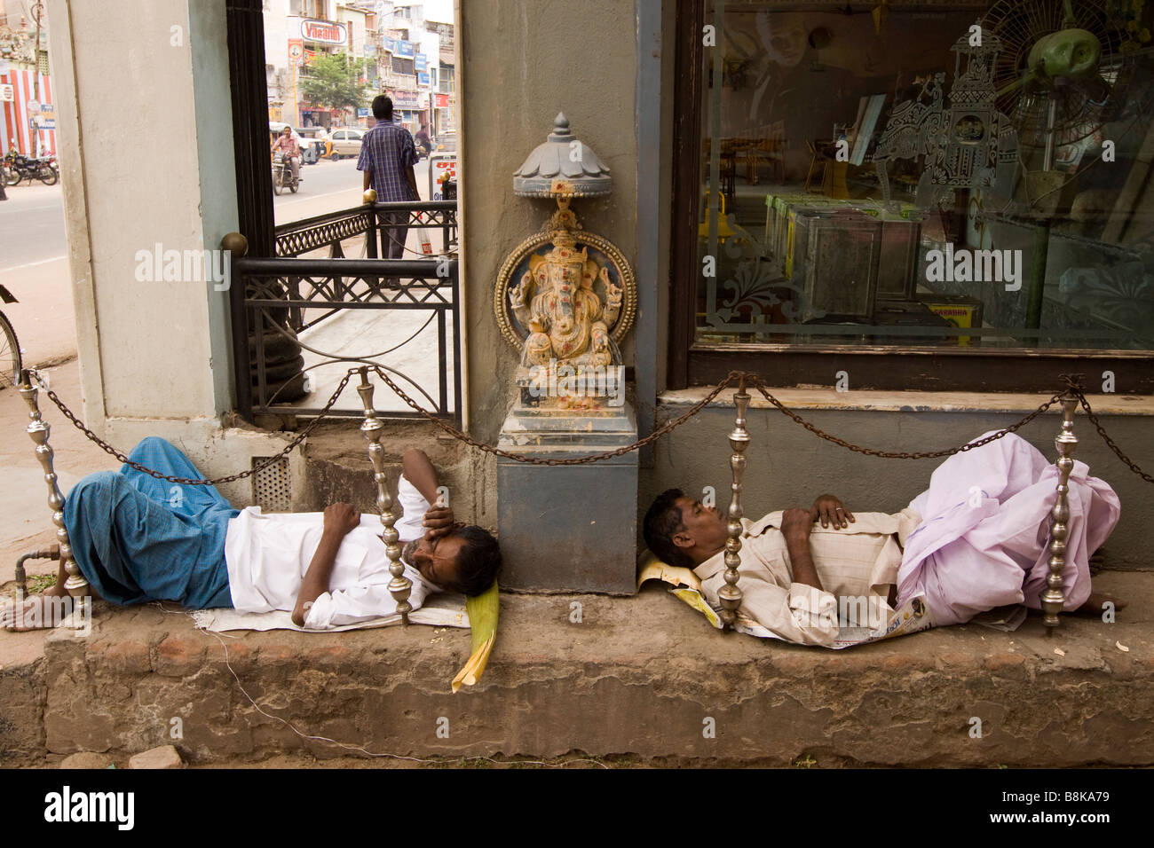 India Tamil Nadu Madurai due uomini dormire in strada accanto alla piccola Hindu Sri Ganesh santuario Foto Stock