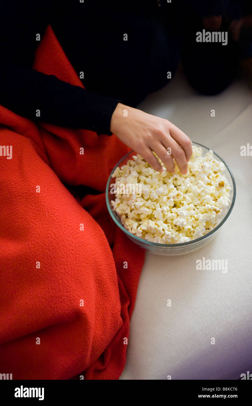 Donna mangiare popcorn sul divano Foto Stock