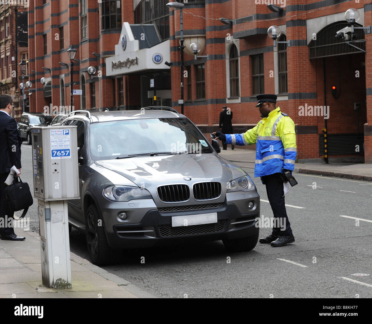 Vigile esecuzione civile Officer a fotografare il disco fiscale di una vettura in Birmingham West Midlands dopo una emissione fissati Foto Stock