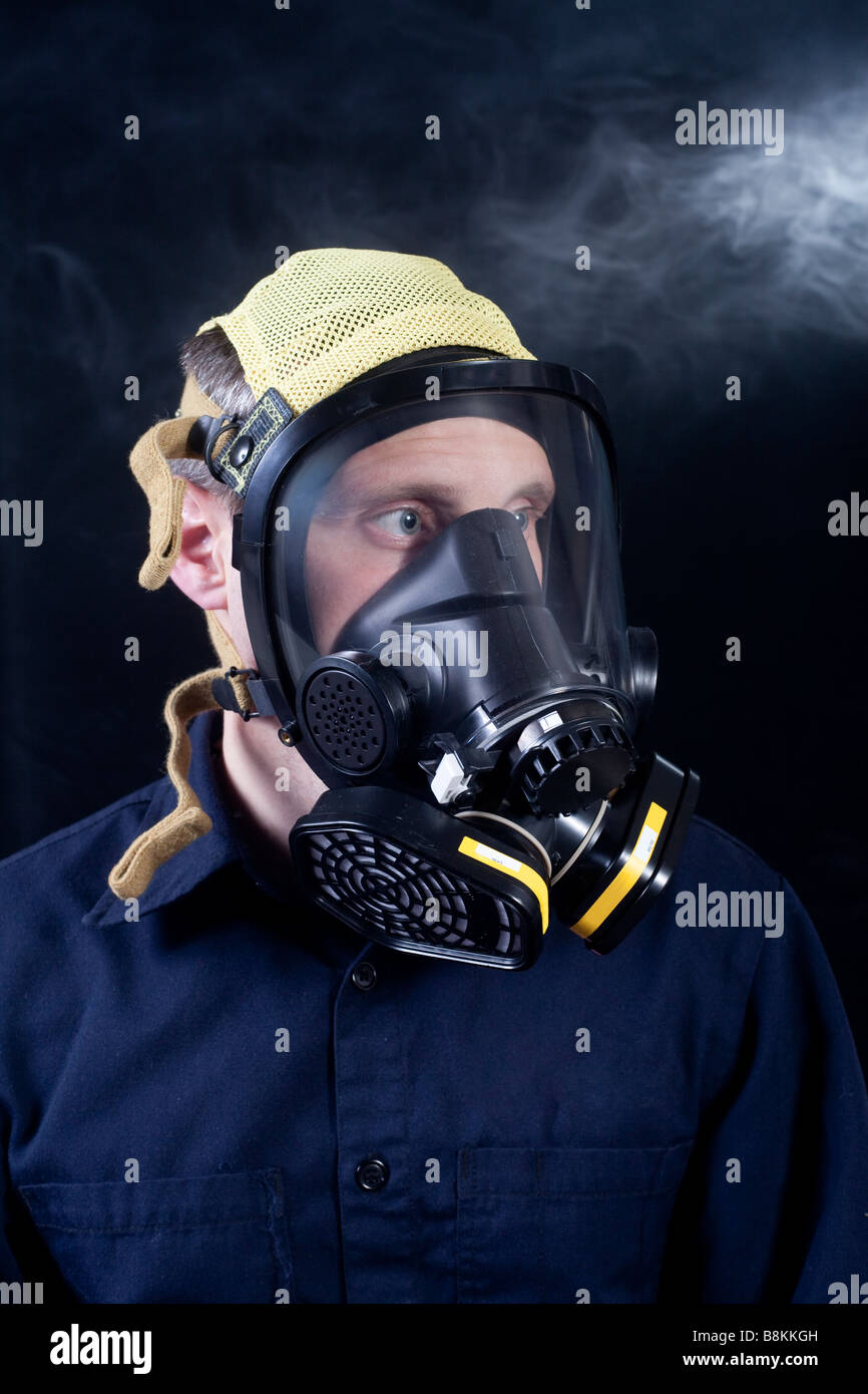 Uomo di indossare il respiratore o maschera a gas mentre esposti a gas tossici o fumo Foto Stock