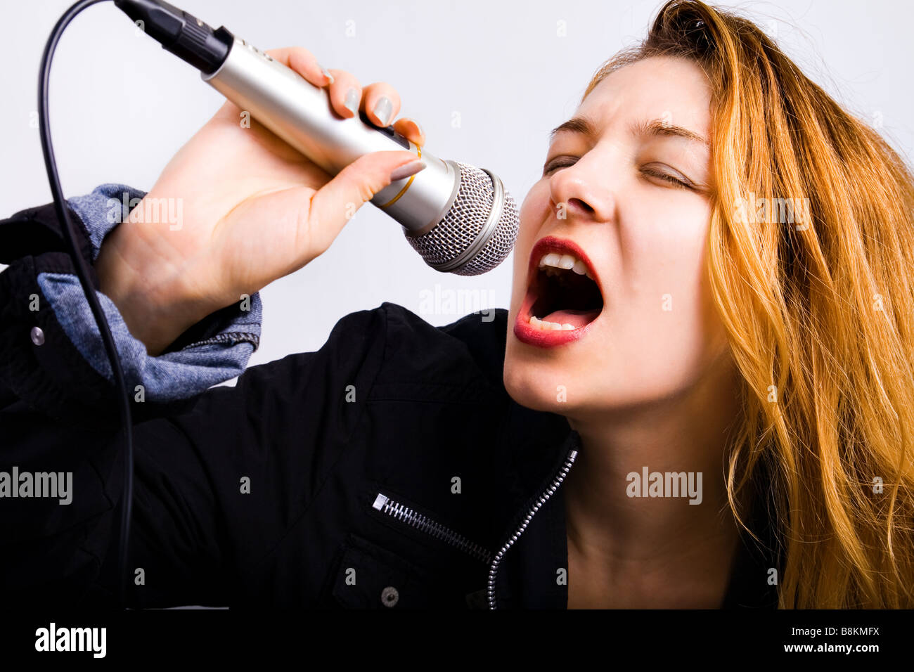 Femmina e giovane cantante karaoke cantando la musica con il microfono Foto Stock