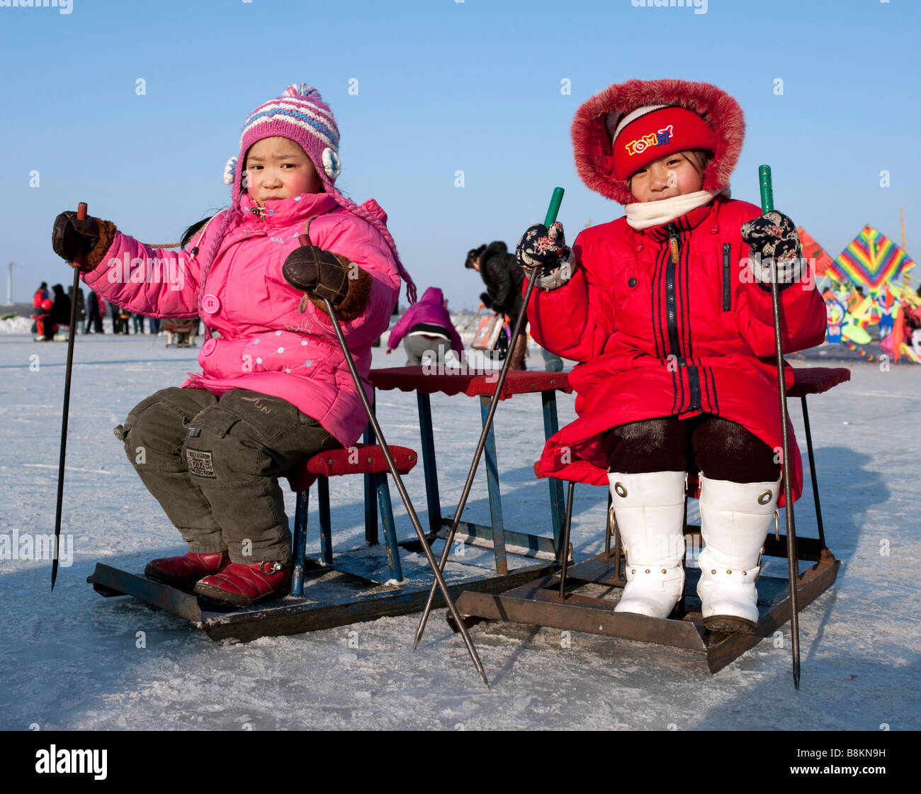Due giovani ragazze su slittini su una pista di pattinaggio su ghiaccio congelato sul fiume Songhua ad Harbin durante l'inverno 2009 Foto Stock