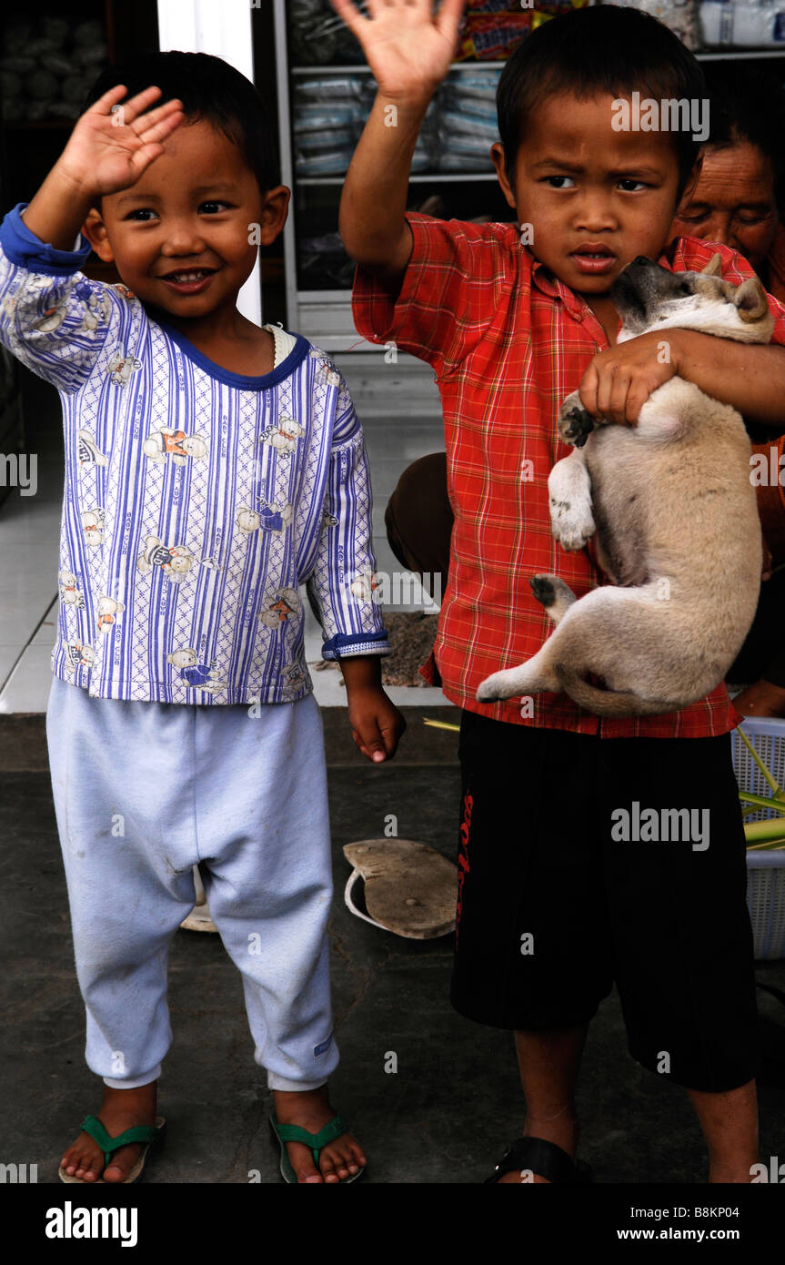 Ragazzi Balinese con cane sventolare le mani per turisti,l'Indonesia. Foto Stock