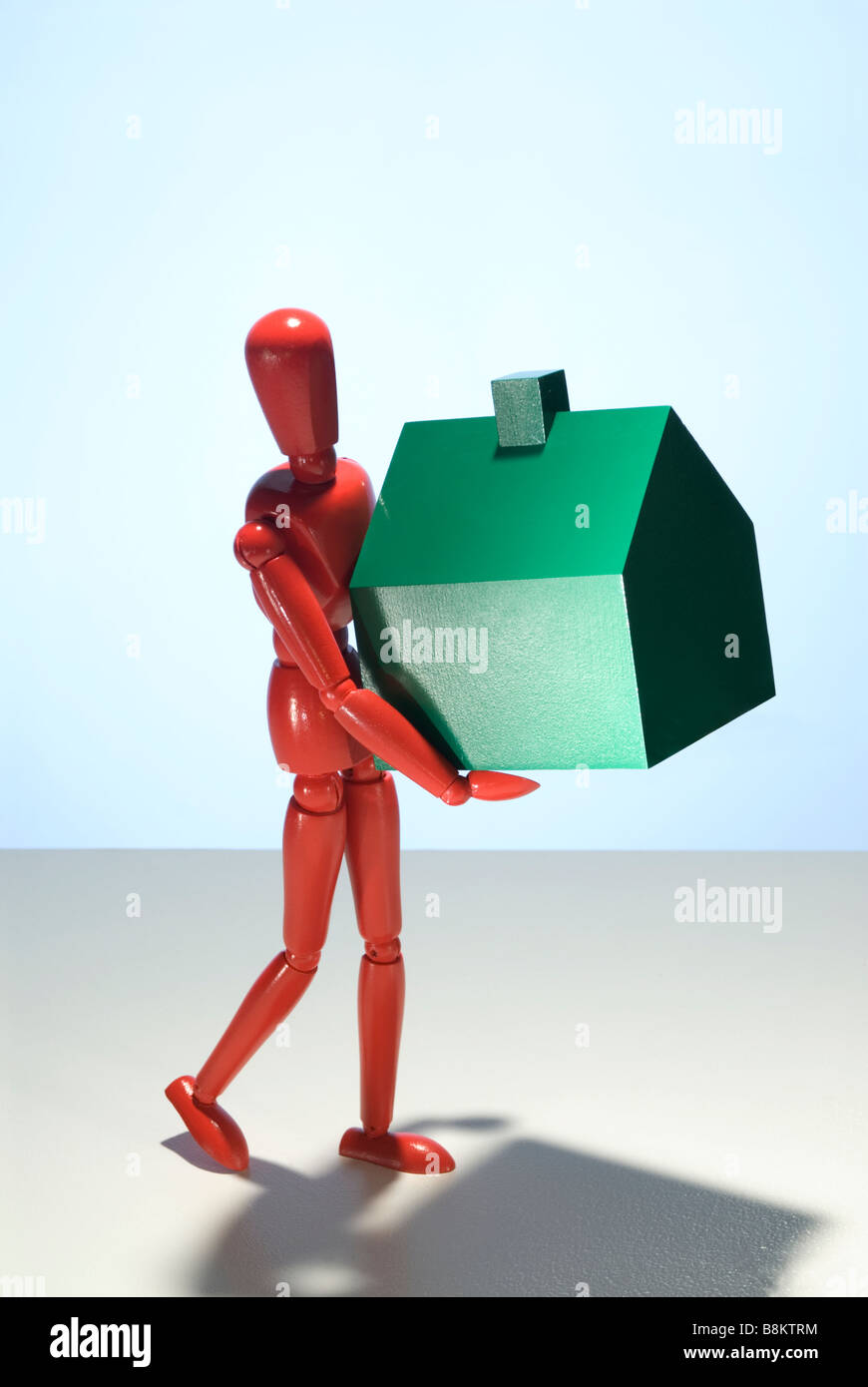Uno rosso manichino di legno figura portante un modello di green house Foto Stock