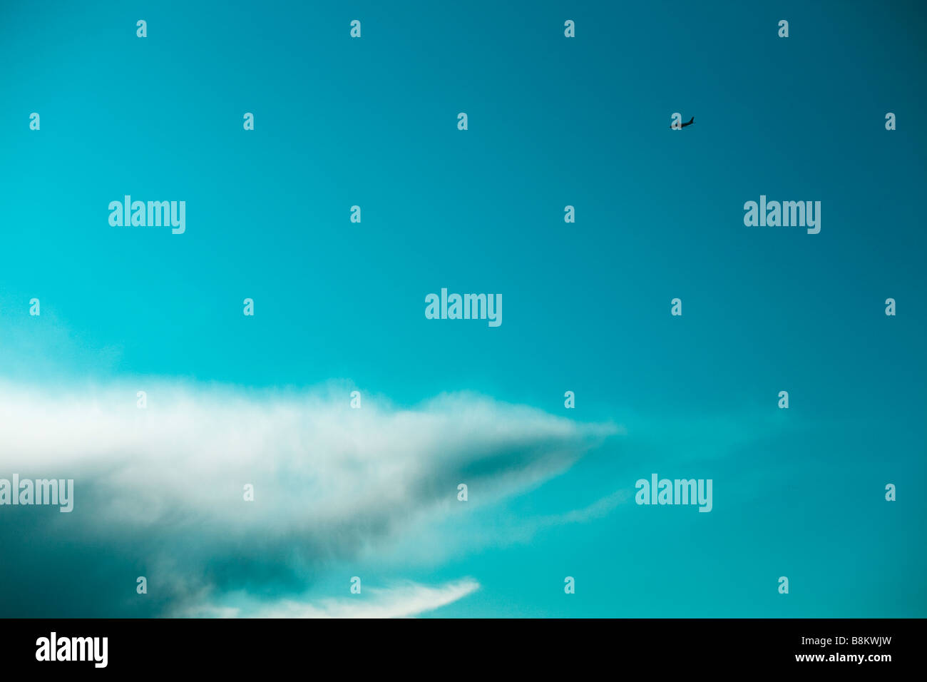 Jet del passeggero volare al di sopra di una nuvola che è sagomata come un squalo Foto Stock