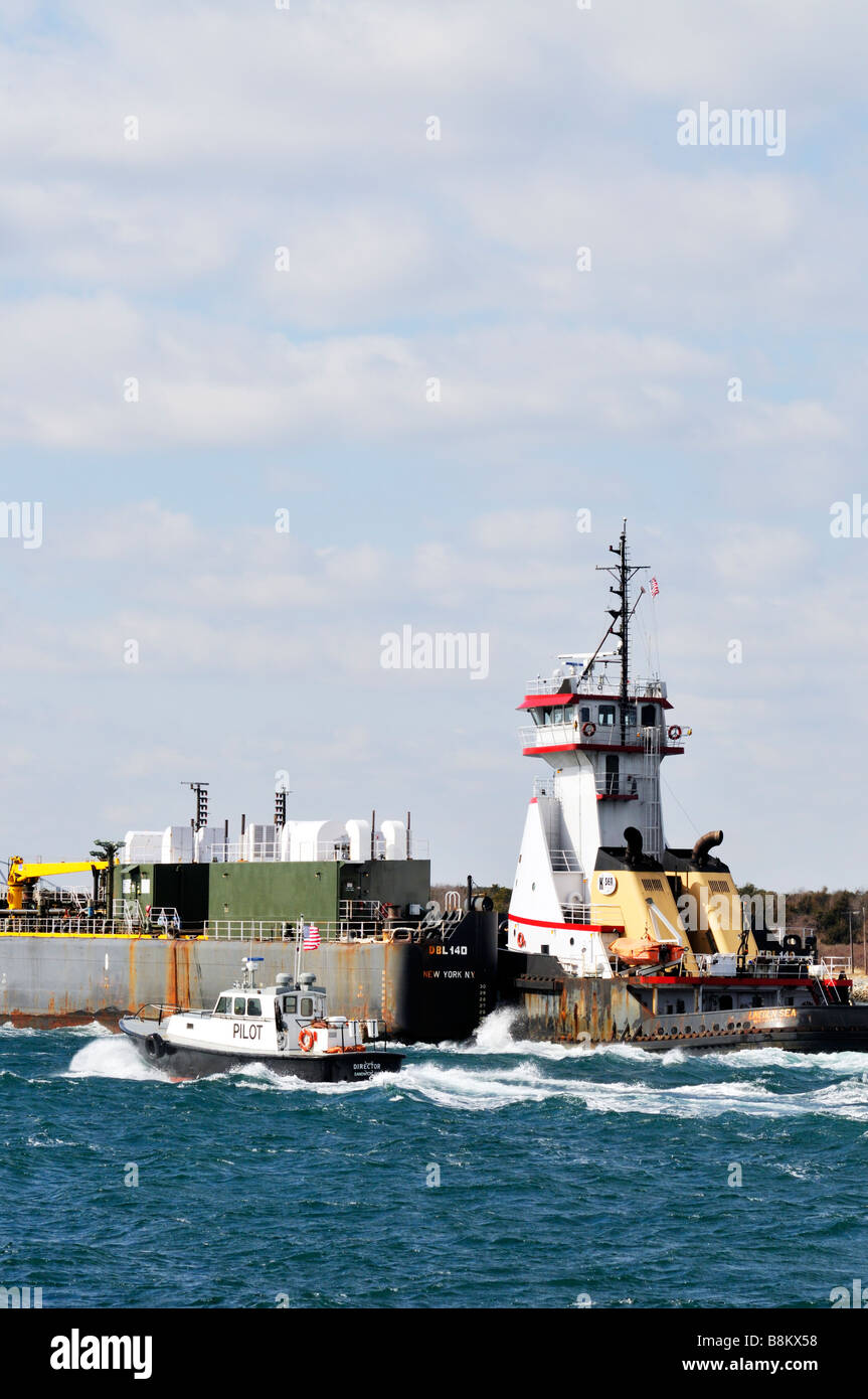 Rimorchiatore spinge un 'double mondati' chiatta di carburante attraverso le acque instabile del "Canale di Cape Cod" con "pilotini" accanto a. Foto Stock