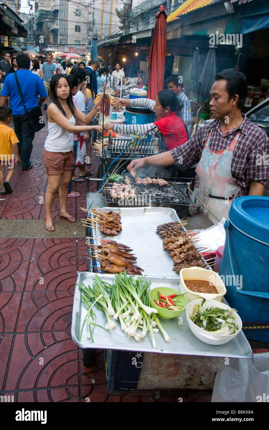 Fornitore di cibo grigliare pollo su un mercato in Chinatown centrale di Bangkok in Thailandia Foto Stock