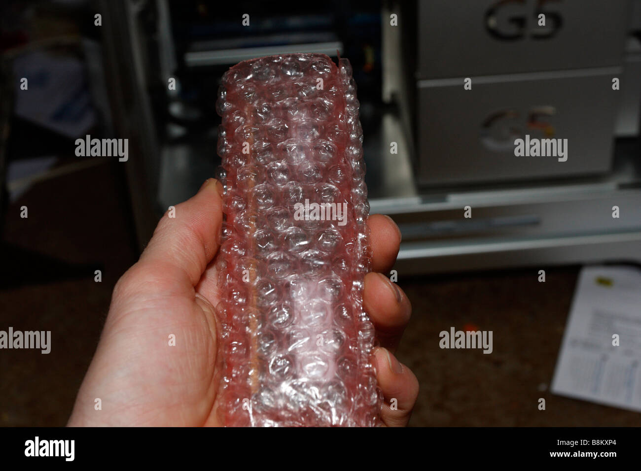 Maschio di mano azienda bolla avvolto di RAM per Apple PowerMac G5, fine 2004 Dual 2 GHz, lato aperto in background. Foto Stock