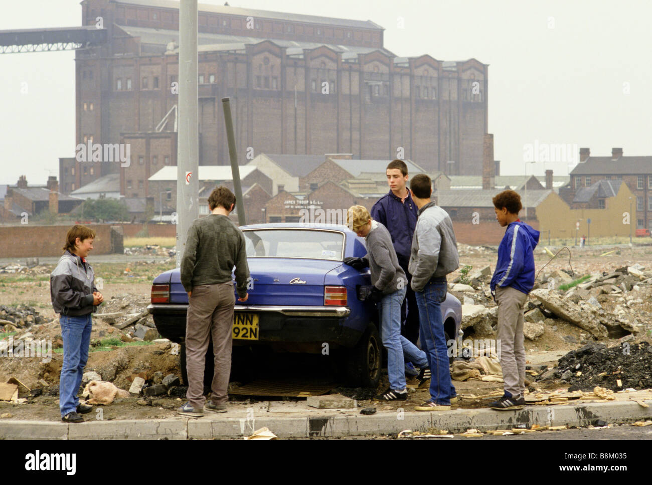 Toxteth Liverpool ragazzi adolescenti circa a vandalise un auto abbandonate sulla massa di rifiuti Foto Stock