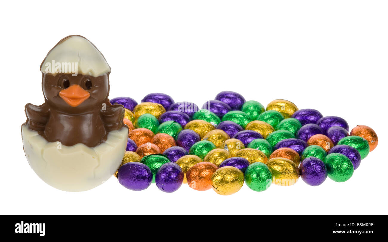 Carino pulcino di pasqua circondato da uova di pasqua di cioccolato isolato su sfondo bianco Foto Stock