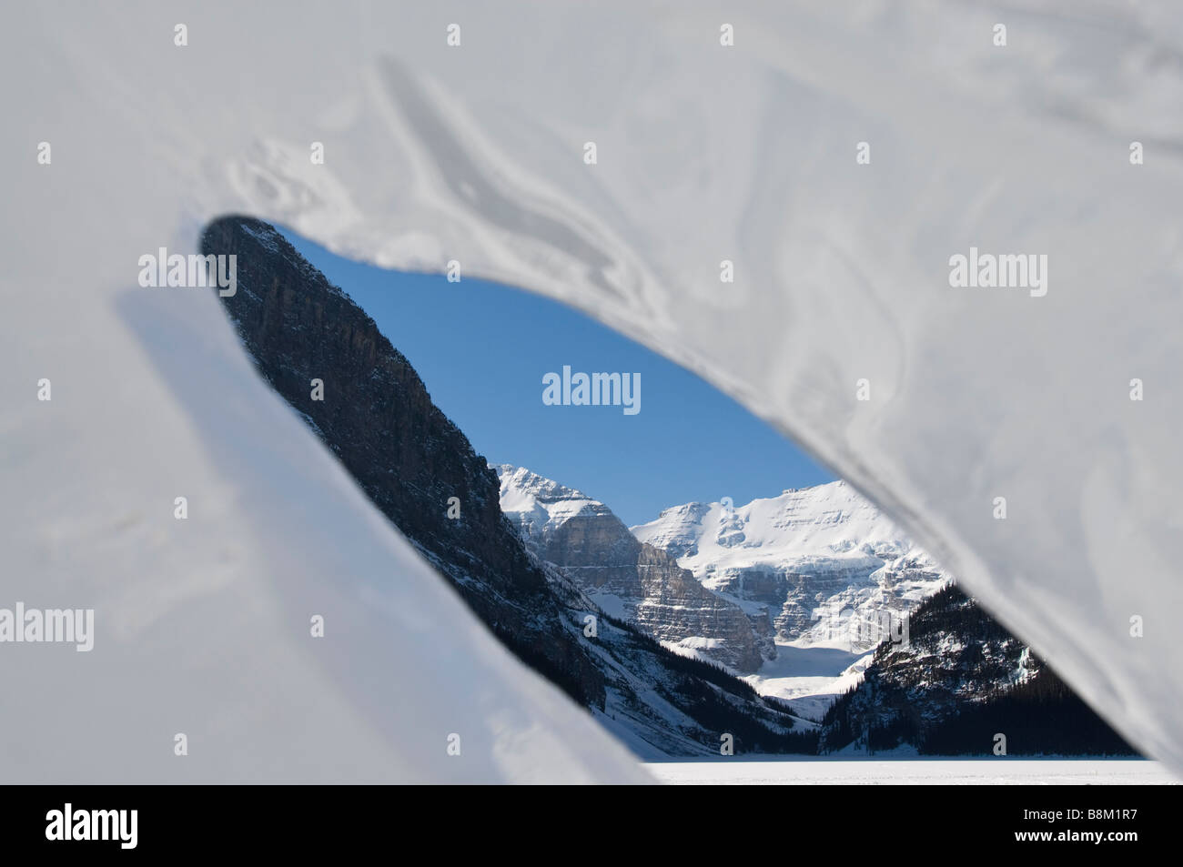 Il lago Louise e le Montagne Rocciose Canadesi in vista attraverso un foro in una scultura di ghiaccio nel Parco Nazionale di Banff, Alberta, Canada. Foto Stock