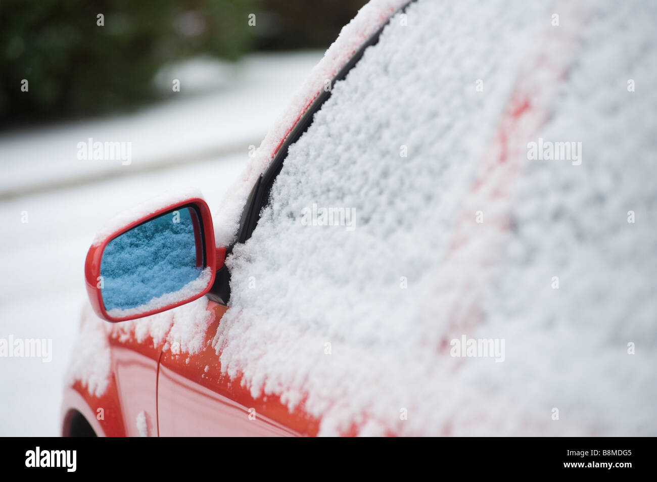 In prossimità di una coperta di neve auto rossa in attesa di essere cancellati su un inverni di mattina Foto Stock