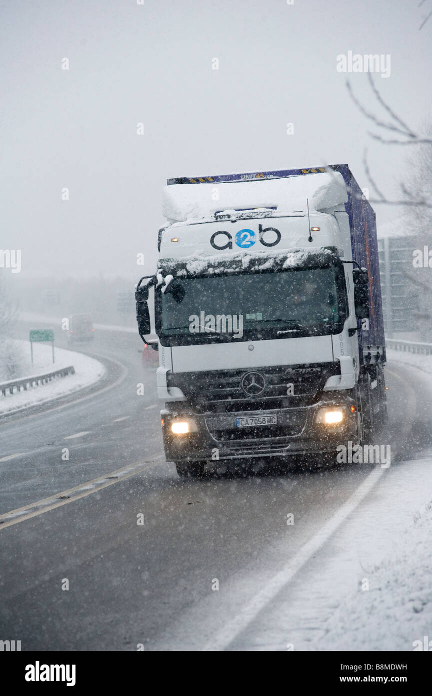 Mercedes Actros HGV autocarro lentamente la guida su una strada innevata in inverno in Inghilterra Foto Stock