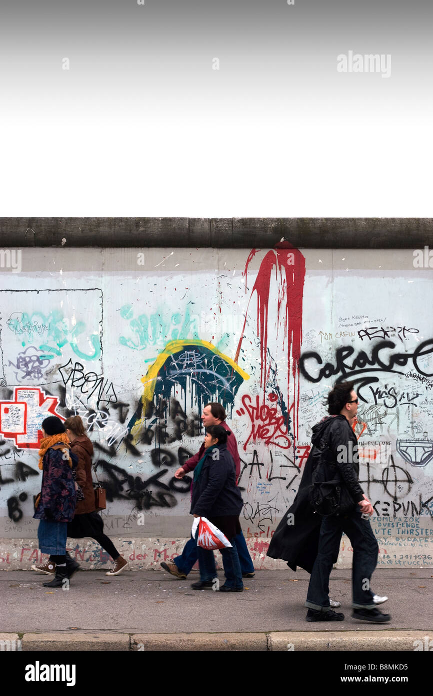 La gente che camminava accanto al muro di Berlino Foto Stock