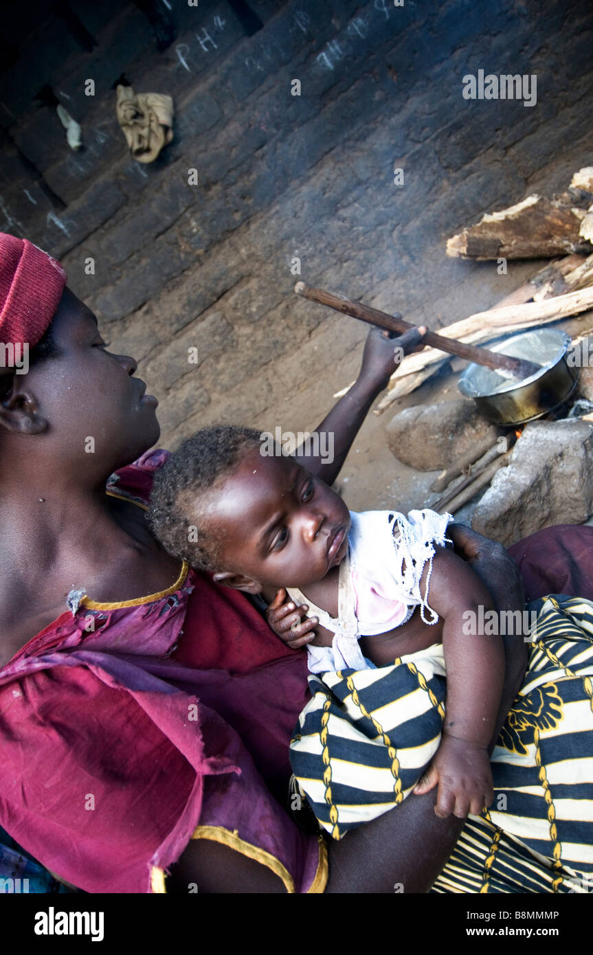 Eunice Chingoma e baby Hannah phala cottura polenta nel suo rifugio Foto Stock