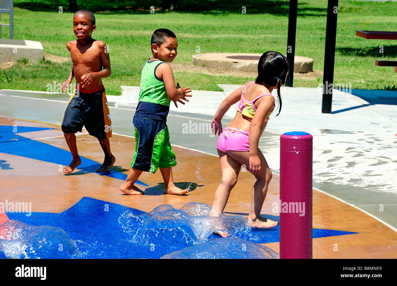 Tre bambini etnicamente diversi giocano in un parco acquatico di Oklahoma City, Oklahoma, USA. Foto Stock