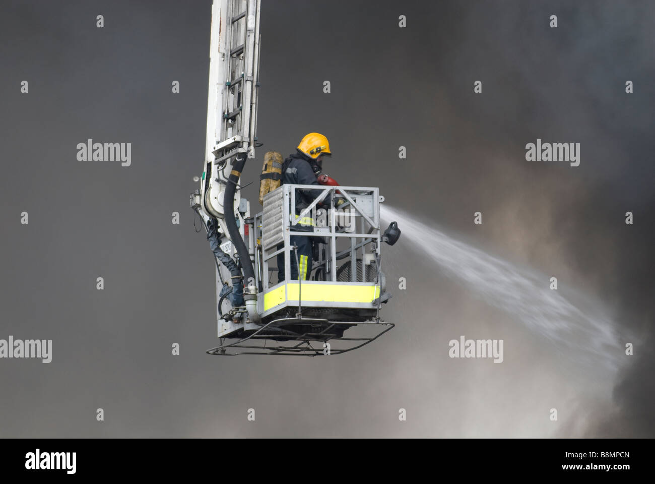 Vigile del fuoco nella piattaforma idraulica gabbia Indossare respiratore combattimenti grande fabbrica di fuoco Foto Stock