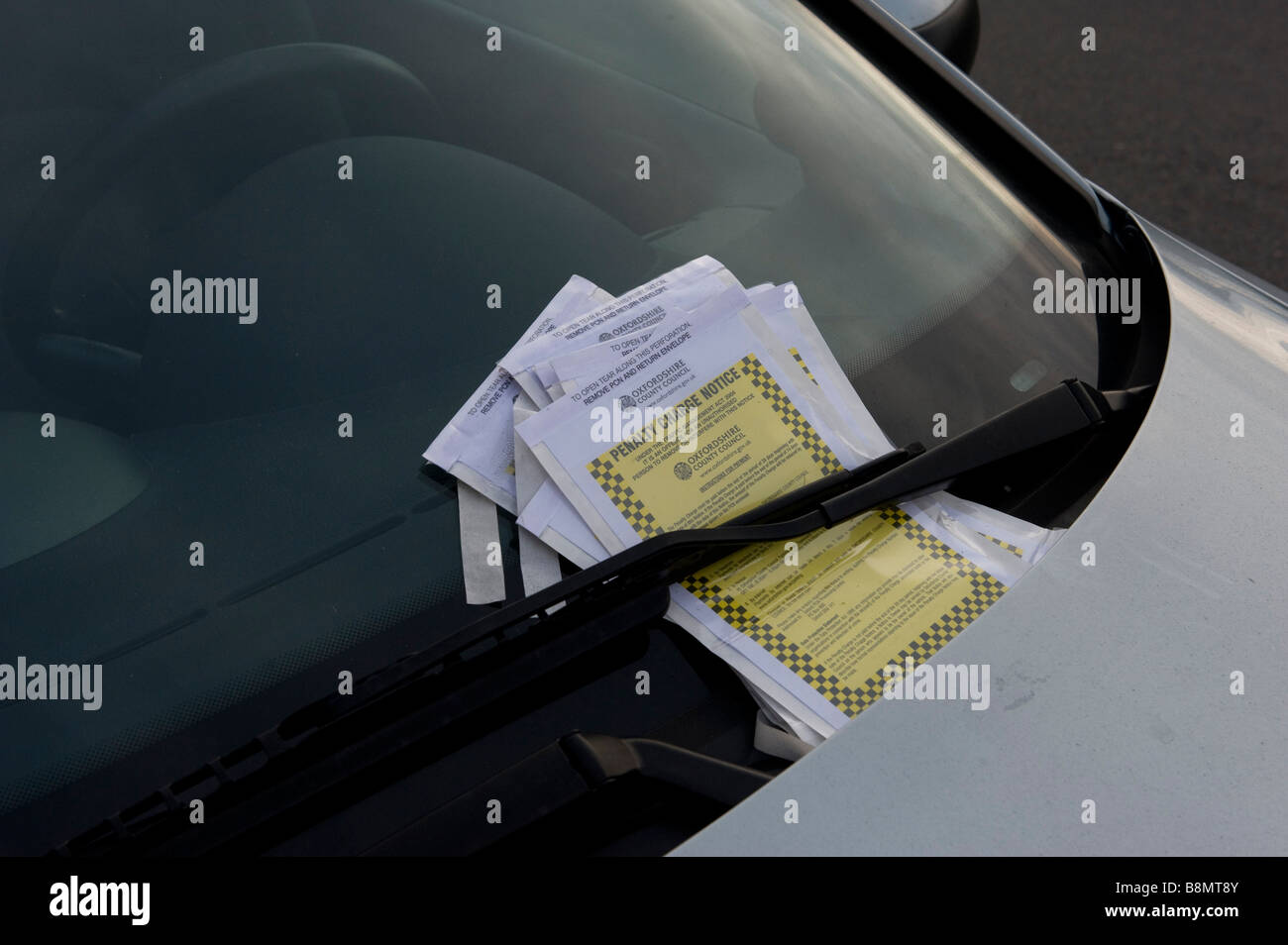 I biglietti per il parcheggio si accumulano su di una vettura parcheggiata illegalmente Foto Stock