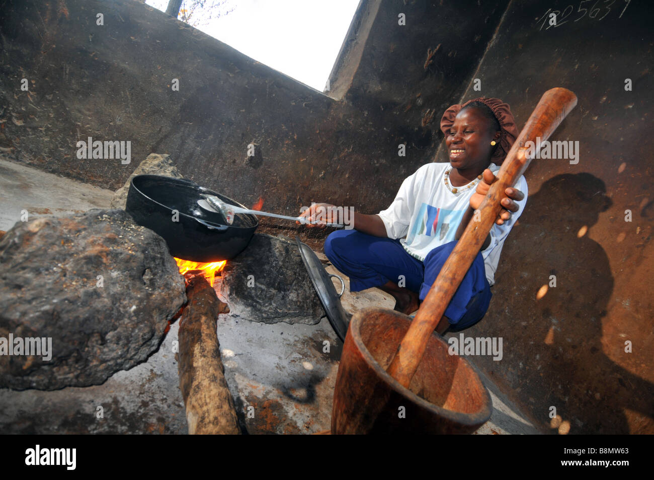La donna per la cottura su un fuoco aperto nella sua base villaggio rurale cucina, Gambia, Africa occidentale Foto Stock