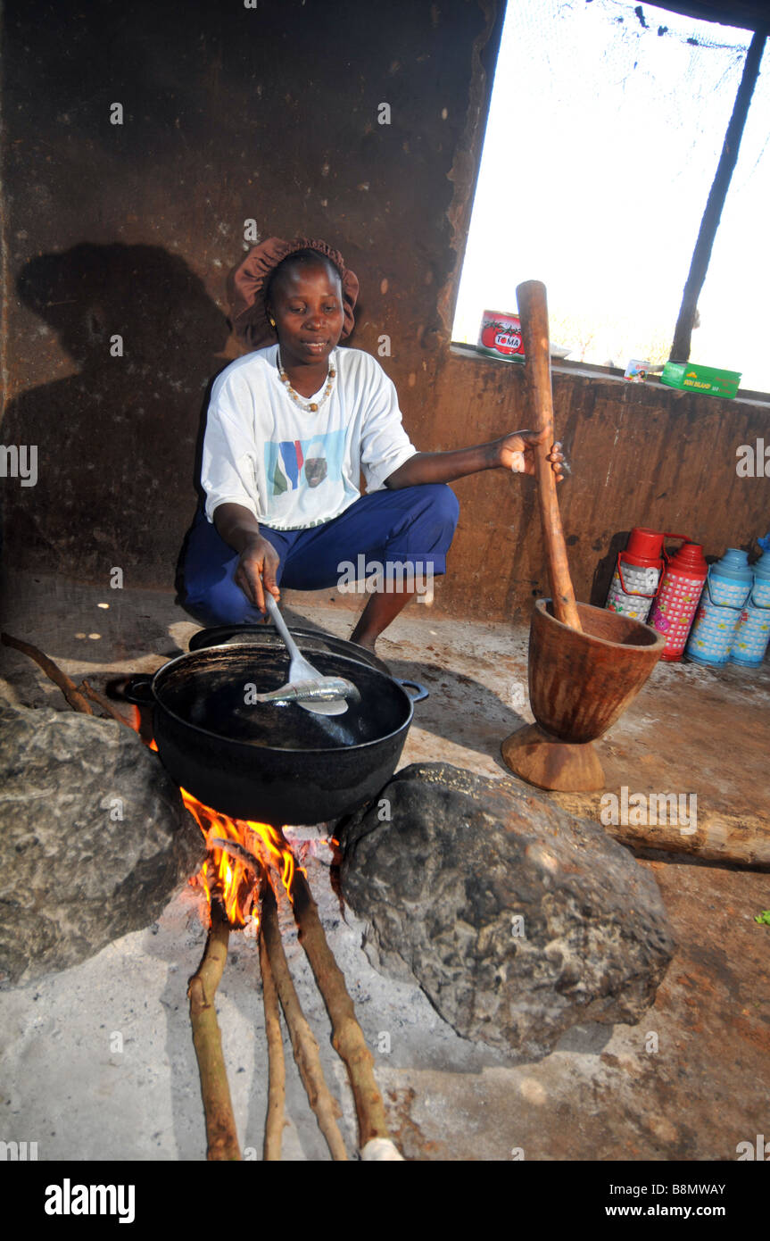 La donna per la cottura su un fuoco aperto nella sua base villaggio rurale cucina, Gambia, Africa occidentale Foto Stock