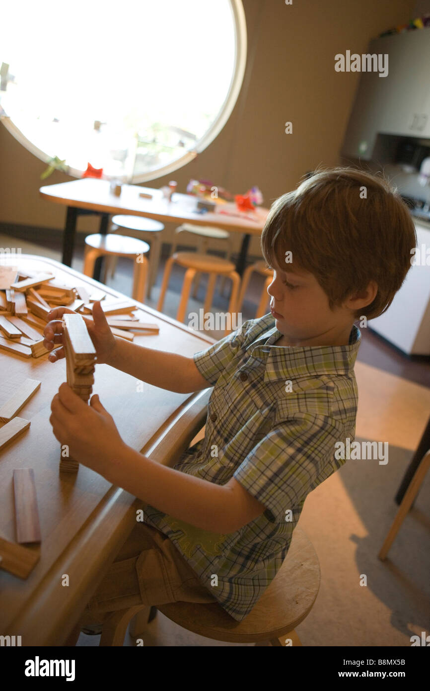 Cinque anni di bambino che gioca con blocchi di legno in corrispondenza di un piano di lavoro Foto Stock
