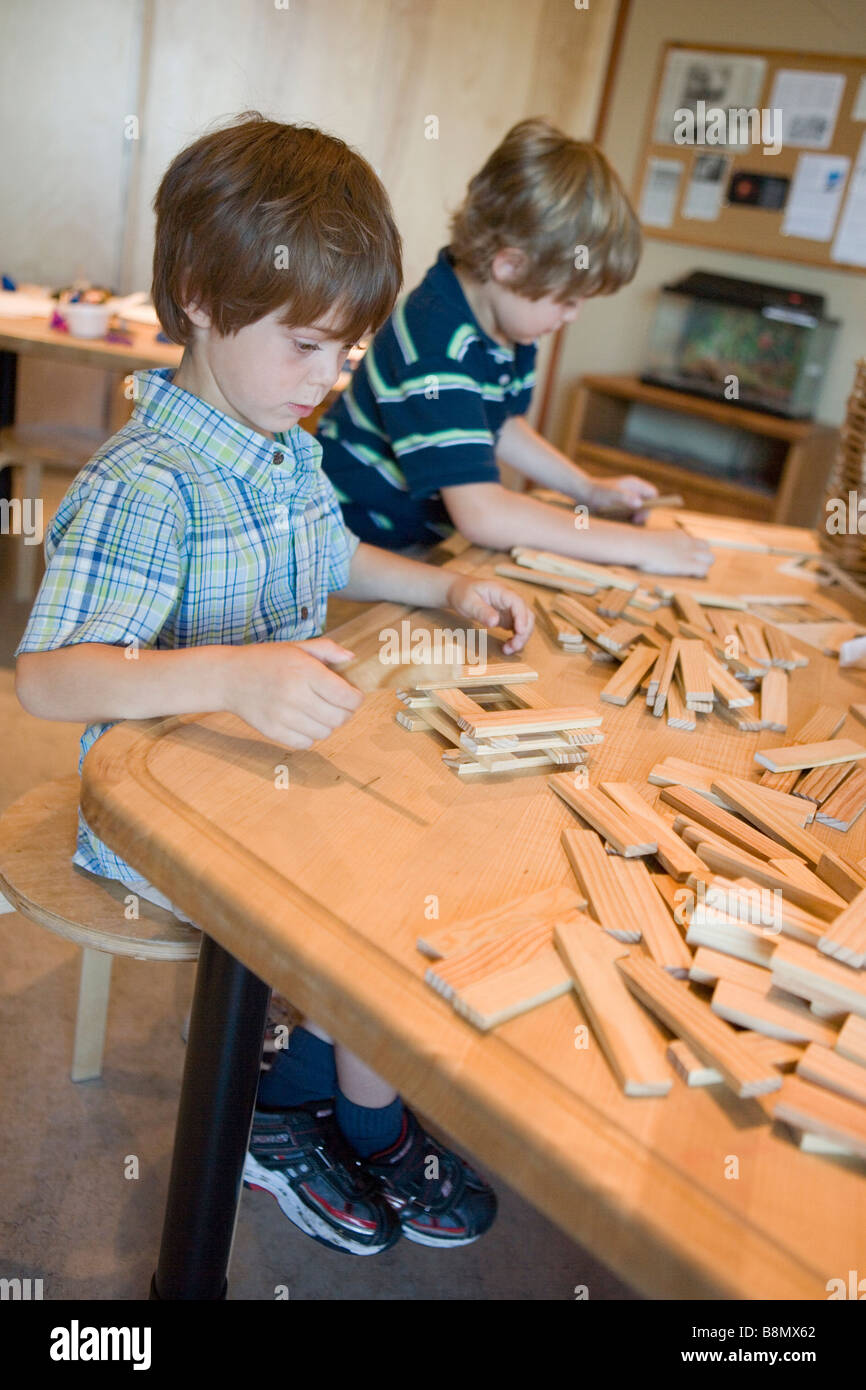 Due bambini di costruzione di case in legno blcoks, imparare a fare una base stabile, tavolo da lavoro, scuola elementare Foto Stock