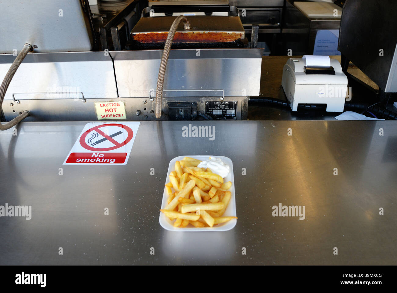Una porzione di chip su un serving hatch con friggitrice in background Foto Stock