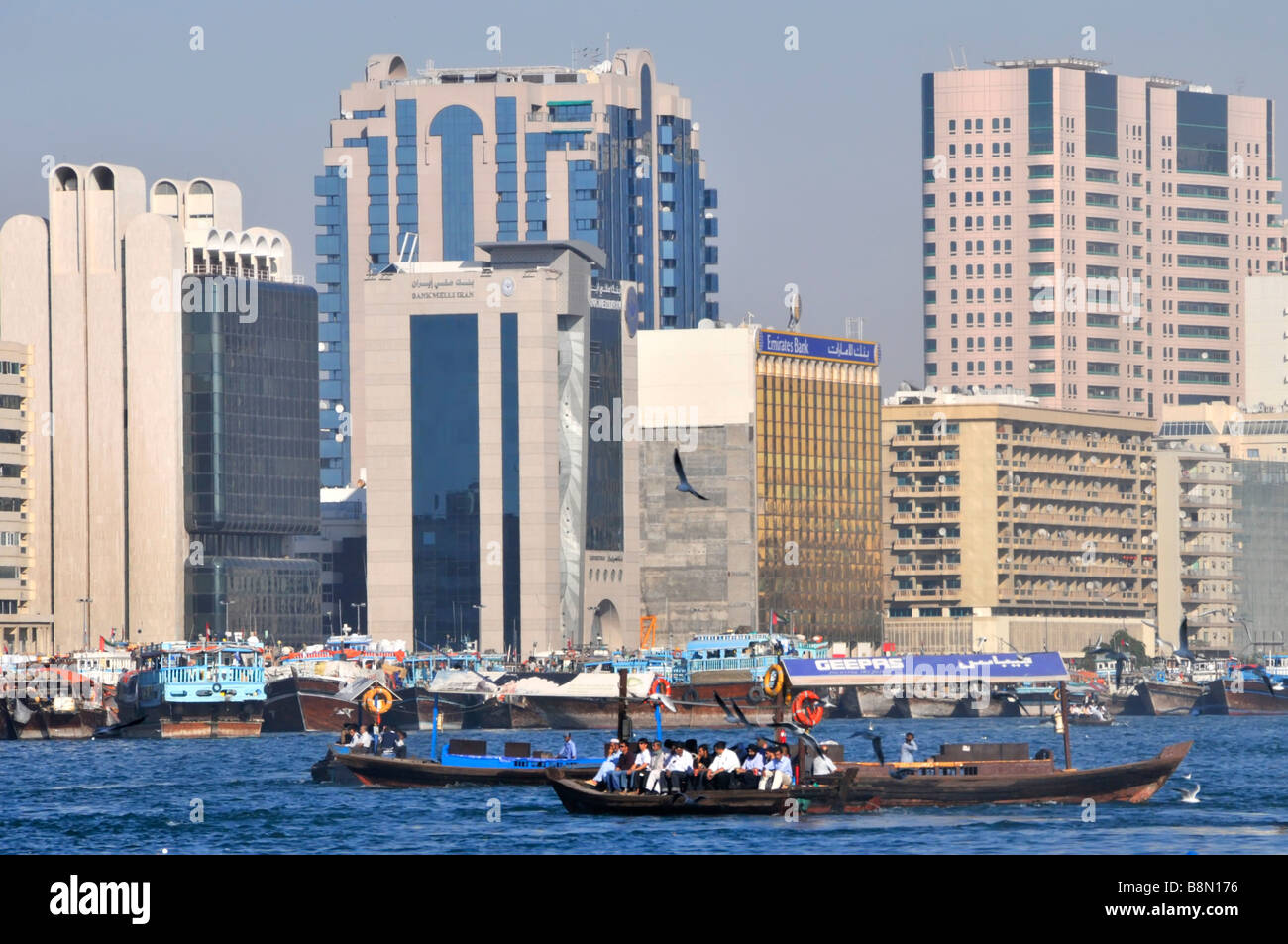 Trasporto in Dubai edificio moderno architettura Dubai Creek grattacielo lungo il fiume Skyline e affollato con Abras taxi d'acqua passeggeri UAE Middle Asia orientale Foto Stock