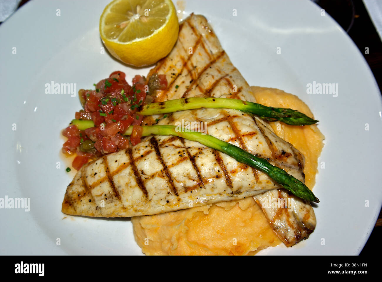 Filetti di grigliate di pesce bianco entree con salsa di pomodoro asparagi su purea di patate rape Foto Stock